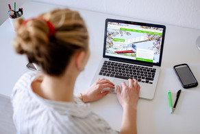 Arbeit am Laptop Am Schreibtisch sitzende Studentin tippt auf dem Laptop, daneben liegen Bücher und Stifte.